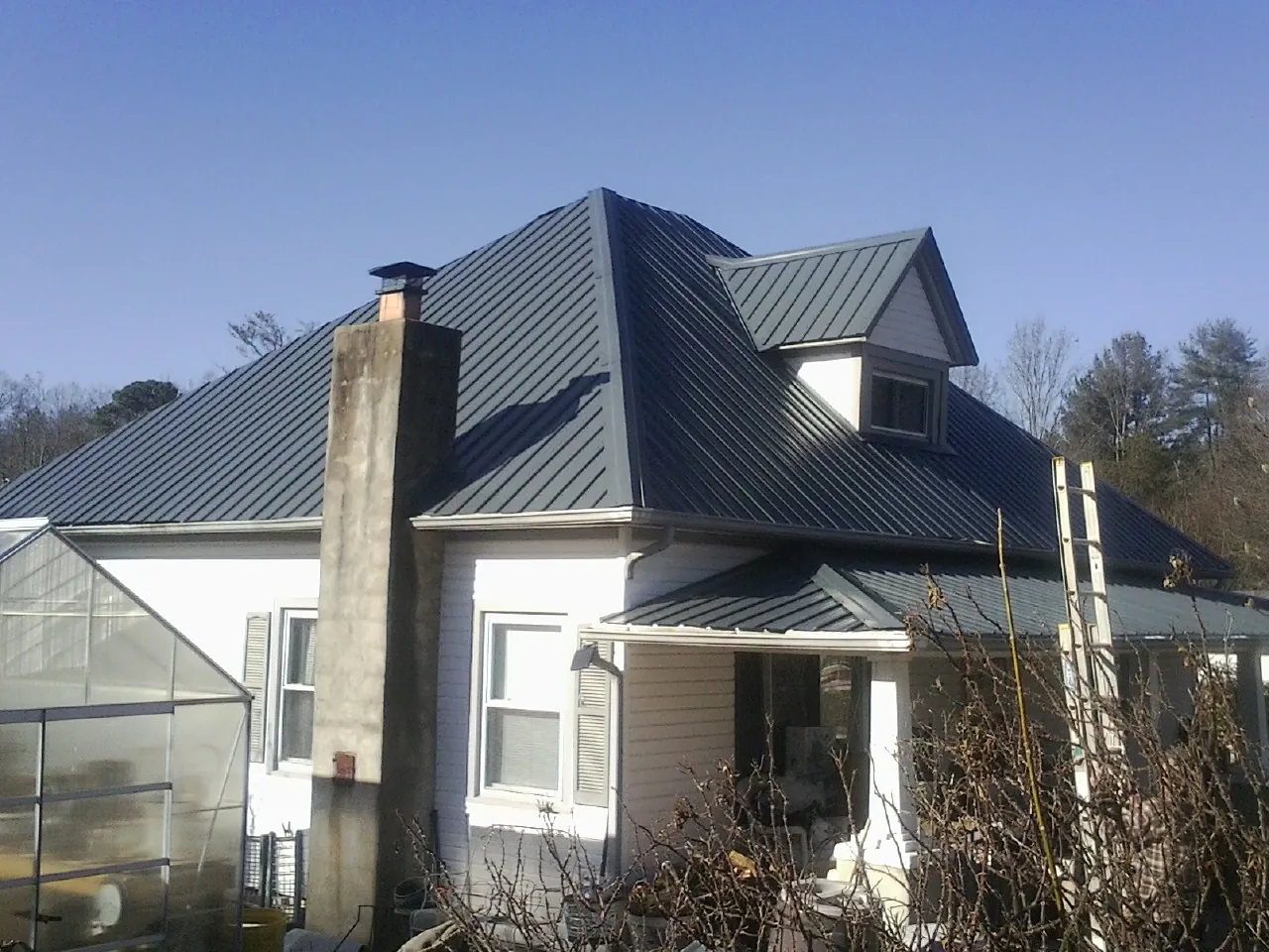 Dark blue standing seam metal roof on a white farmhouse with dormer — Slate & Tile Roof Repair by Roofing Brothers in Chalfont