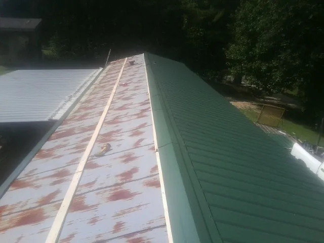 Old rusted panels beside newly installed green metal roofing — Wind Damage Roof Repair by Roofing Brothers in Chalfont