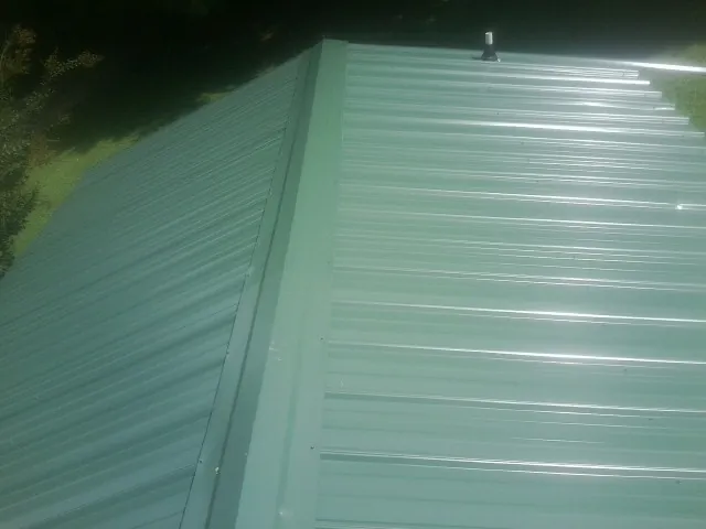 New green metal panels meeting at the ridge of a roof — Flat Roof Repair work by our crew in Chalfont