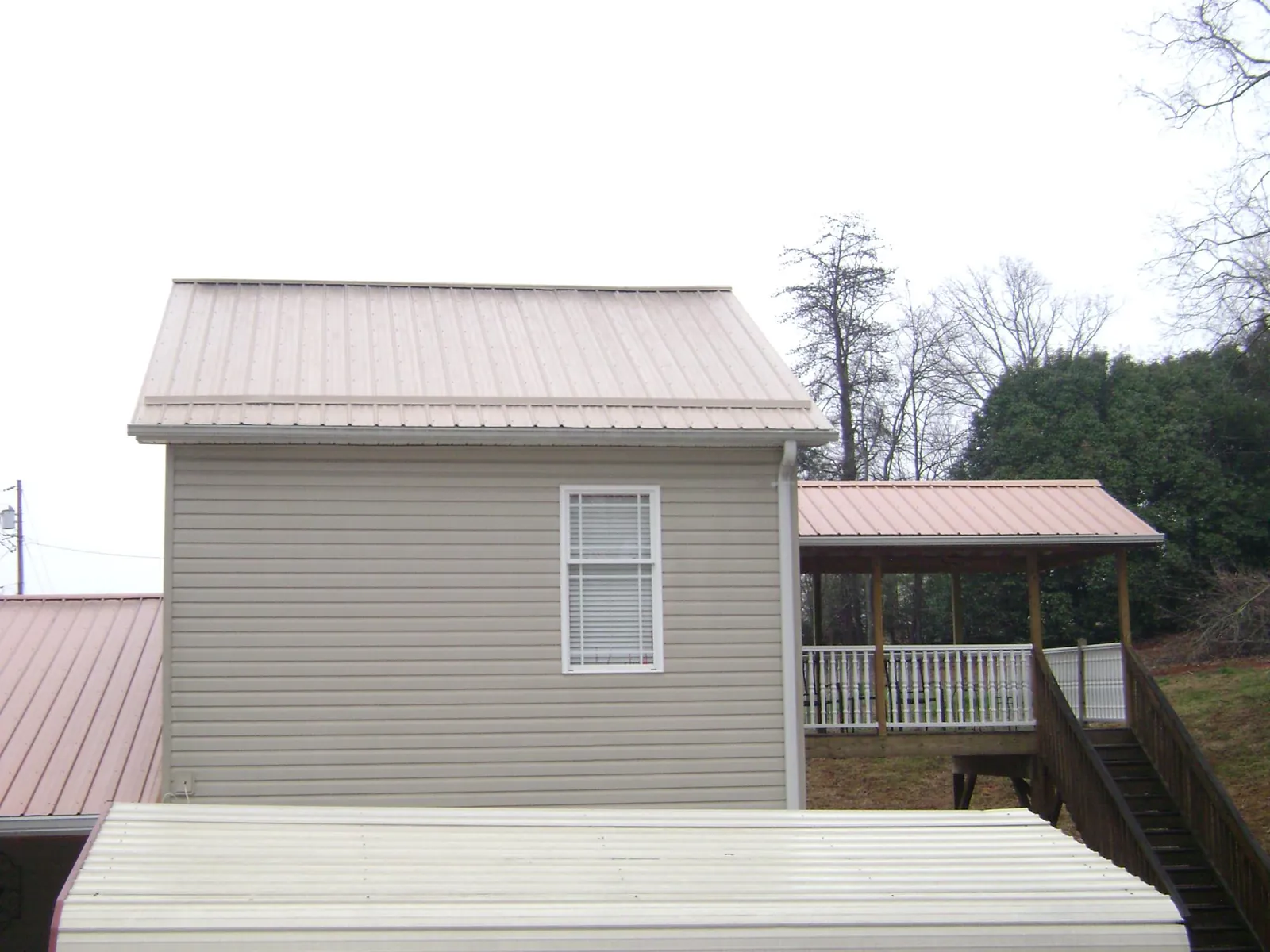 Tan metal roofs on a two story addition and attached porch, from a Roof Replacement job in Chalfont