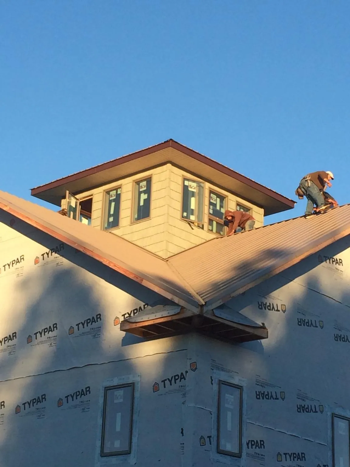 Roofers working around a rooftop cupola on a new metal roof at sunset — Roof Waterproofing in Chalfont by Roofing Brothers